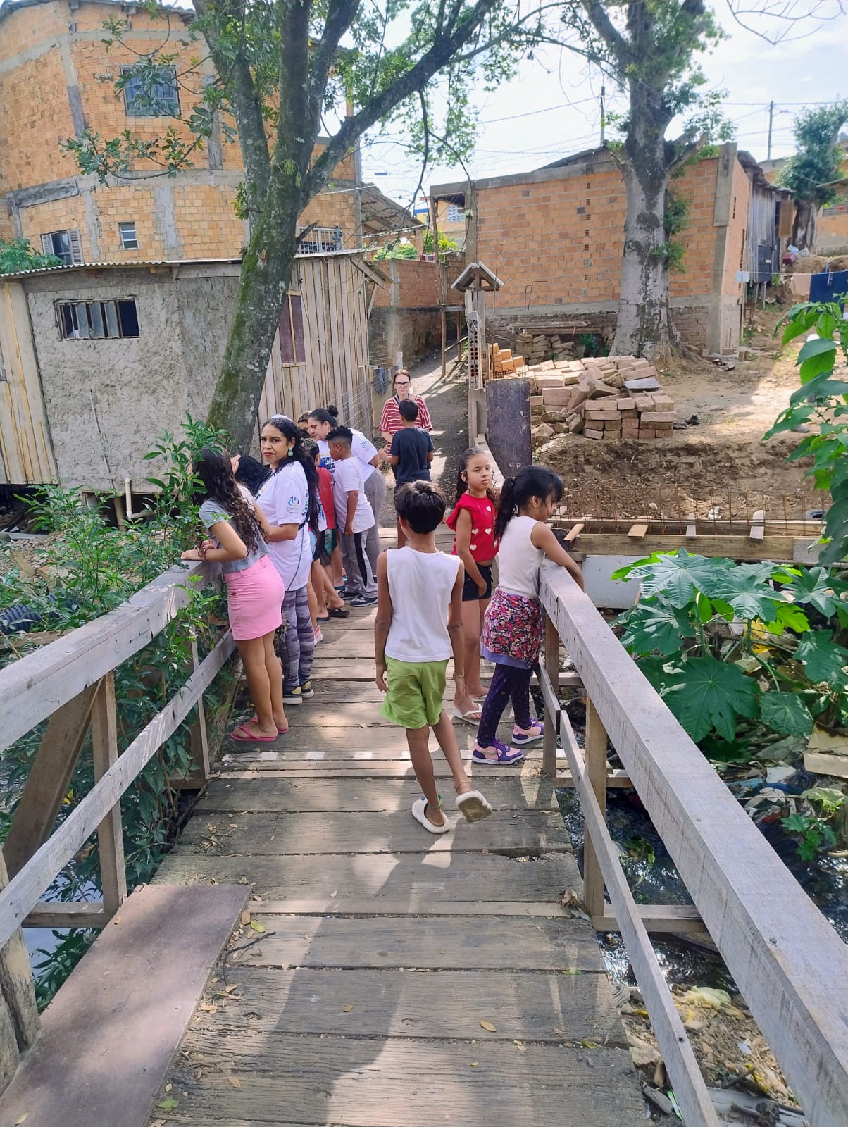 Crianças e professora Silvia caminhando pelo território e olhando a sanga.